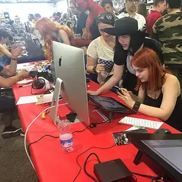 Due ragazze provano una tavoletta grafica allo stand della Scuola di Fumetto al Rimini Comix – 2019